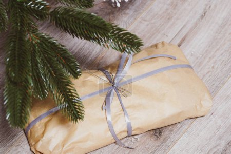 A roll of paper tied with a ribbon under a fir tree. Present. Christmas gifts concept