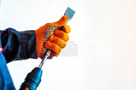 Photo for Close-up. hands in protective gloves, hammer drill, installation of a chisel in a perforator. The concept of replacing the rotary drill. - Royalty Free Image