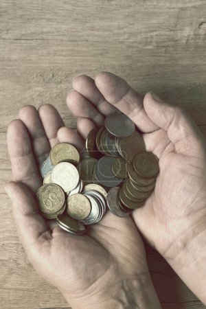 Münzen in den Handflächen. Geld in der Hand. Armutskonzept, Geldknappheit. Auf einer Münze steht auf Ukrainisch - 50, 25 und 5 Kopeken.