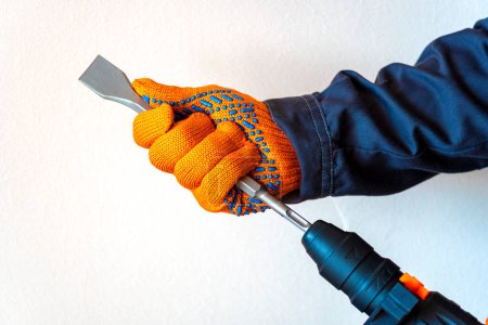 close-up. hands in protective gloves, hammer drill, installation of a chisel in a perforator. The concept of replacing the rotary drill.
