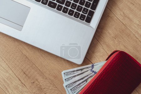 Geldbörse mit Geld auf Laptop-Hintergrund. Brieftasche mit Dollars. Online-Einkauf, Internet-Verkauf. Einkaufen im Internet. Ansicht von oben