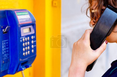 Das Mädchen hält eine Payphone-Tube in der Hand. Ein Anruf von der Kasse. Das Konzept Zugang vor telefonischer Kommunikation. Ein Anruf aus der Öffentlichkeit..