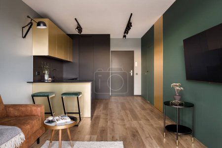 Téléchargez les photos : Aménagement ouvert, appartement moderne avec murs verts, détails dorés et plancher en bois - en image libre de droit