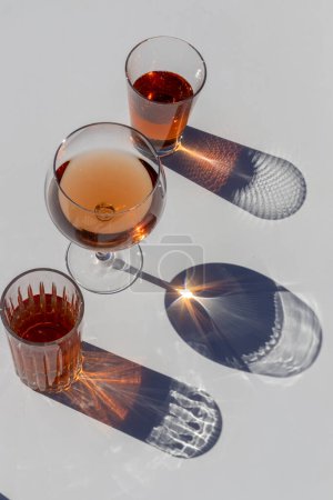 glasses and a cocktail with ice and two glasses of wine on a white surface.