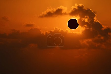 Eclipse en la naranja del cielo del atardecer y la espalda pequeña nube suave