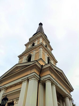 Foto de Una vista desde abajo de la torre de la iglesia ortodoxa tocando el cielo nublado de otoño con una cruz. - Imagen libre de derechos