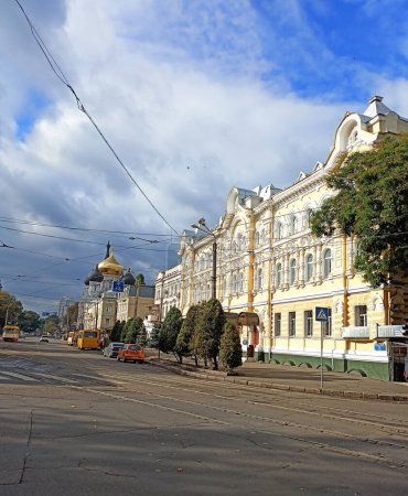 Foto de Un panorama de un antiguo edificio y una iglesia ortodoxa en la avenida Odesa bajo los rayos del sol de otoño de la mañana sobre el fondo de un cielo azul, apenas nublado. - Imagen libre de derechos