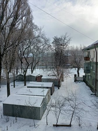 Foto de Una vista desde el balcón de un bloque residencial en las afueras de la ciudad cubierta de nieve suave rodeada de árboles cubiertos de nieve contra un cielo nublado de invierno. - Imagen libre de derechos