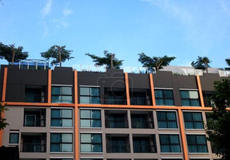 Foto de Vista frontal del edificio residencial moderno y cielo azul brillante, árbol y jardín en la parte superior del edificio, Tailandia. - Imagen libre de derechos