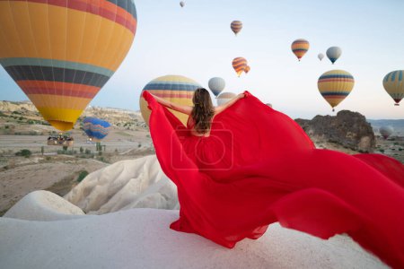 Téléchargez les photos : Une fille en robe volante avec un long train sur fond de ballons en Cappadoce - en image libre de droit