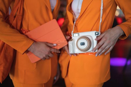Foto de Dos promotoras en trajes idénticos con una cámara y una tableta - Imagen libre de derechos