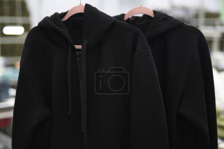 Photo for Black hoodie clothes hang on hangers at the factory - Royalty Free Image