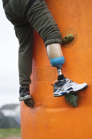 a man with a prosthetic leg does sports climbing on a climbing wall
