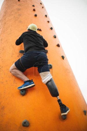 a man with a prosthetic leg does sports climbing on a climbing wall