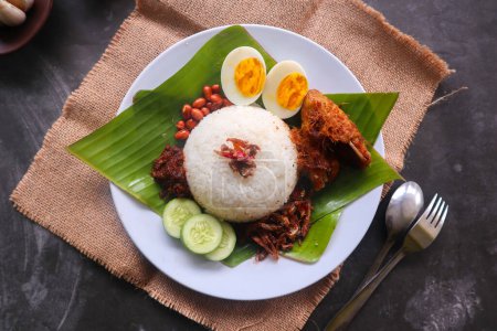 Foto de Nasi lemak, es tradicional malayo hecho huevos hervidos, frijoles, anchoas, salsa de chile, pepino. del plato servido sobre una hoja de plátano - Imagen libre de derechos