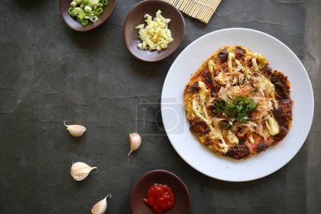 Téléchargez les photos : Okonomiyaki, pizza japonaise traditionnelle, pizza japonaise à assiette chaude d'Okonomiyaki. faite de farine qui est diluée avec de l'eau ou du dashi, plus le chou, les œufs de poulet, les fruits de mer et frits dans une teppan - en image libre de droit