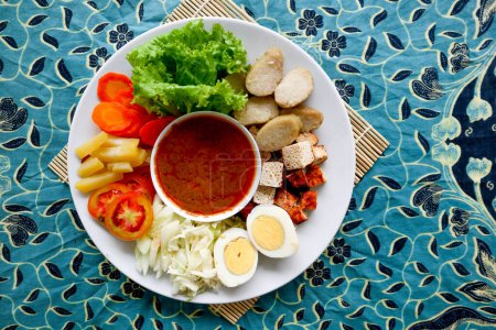 Téléchargez les photos : Gado-gado est une salade traditionnelle indonésienne composée de légumes, pommes de terre, tempeh, tofu, carottes, tomates, laitue, œufs, gâteau de riz et sauce aux arachides. Salade - en image libre de droit