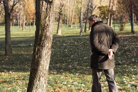 Photo for Pensive senior man walking at park - Royalty Free Image