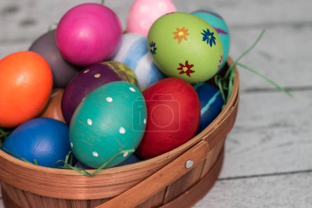 Photo for Basket with painted colorful easter eggs on wooden table - Royalty Free Image