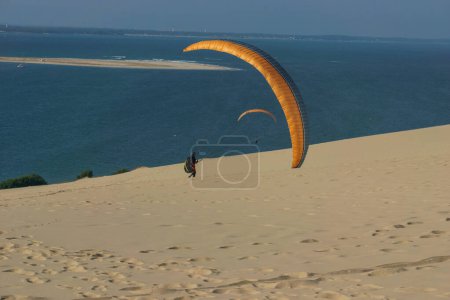 Téléchargez les photos : Parapente individuel avec parachute à la dune de Pilat par une journée ensoleillée, Arcachon, Nouvelle-Aquitaine, France - en image libre de droit