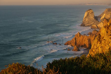 Photo for Golden illuminated rocks during sunset at atlantic ocean coast on westernmost point, Cape Roca, Cabo da Roca, Portugal. - Royalty Free Image