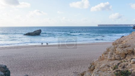 Dos surfistas en la playa Praia do Tonel caminando con tablas en el mar, Sagres, Algarve, Portugal
