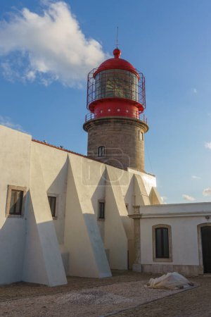 Tower of the lighthouse at Cabo de Sao Vicente with blue cloudy sky in golden sunlight, Sagres, Algarve, Portugal