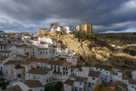 Blick auf ein typisch andalusisches Dorf mit weißen Häusern und Straße mit in Felsüberhänge eingebauten Wohnhäusern, Setenil de las Bodegas, Andalusien, Spanien