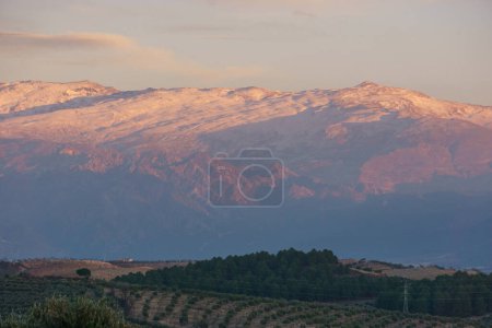 Landschaft der Sierra Nevada mit schneebedeckten Berggipfeln bei Sonnenuntergang in der Nähe von Granada, Andalusien, Spanien