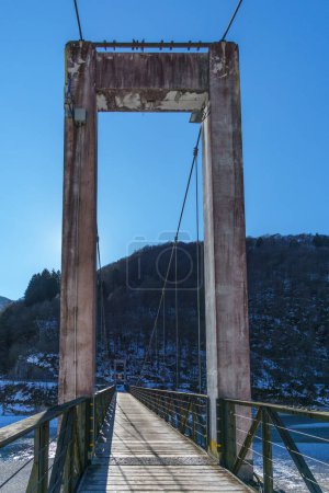 Puente de metal colgante sobre el lago Barcis a lo largo de la senda Dint en invierno, Barcis, Friuli-Venezia Giulia, Italia