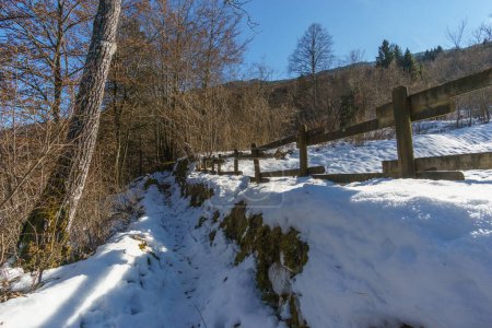 Wanderweg neben Zaun in einer verschneiten Winterlandschaft in den Alpen, Barcis