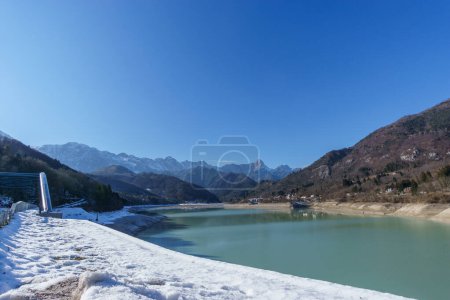 Lago embalse durante el invierno con pueblo en el paisaje de montaña de los Alpes, Barcis, Friuli-Venezia Giulia, Italia