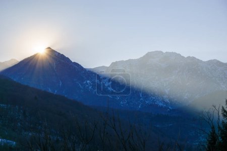 Winter sun behind a mountain peak of a winter alpine landscape at Barcis, Friuli-Venezia Giulia, Italy