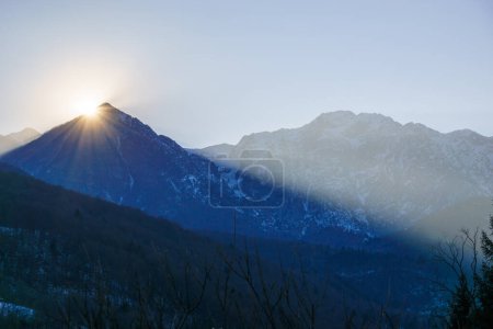 Soleil d'hiver derrière un sommet de montagne d'un paysage alpin d'hiver à Barcis, Frioul-Vénétie Julienne, Italie