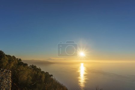Téléchargez les photos : Baie méditerranéenne vue du belvédère de Monte Sant'Elia au coucher du soleil avec de la fumée s'élevant du volcan Etna actif en Sicile, Palmi, Calabre, Italie - en image libre de droit