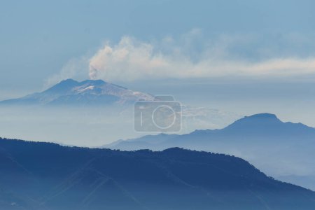Téléchargez les photos : Fumée montant du volcan Etna actif en Sicile par un jour bleu brumeux vu de Palmi, Calabre, Italie - en image libre de droit