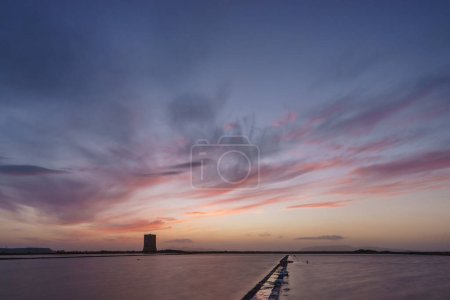 Vibrant sky during evening twilight after sunset at nature reserve Saline di Trapani with salt fields and Torre Nubia, Contrada Nubia, Sicily, Italy