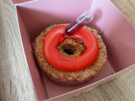 Photo for Cronut - a donut made from croissant dough - with pink fruit topping and a vial of liqueur to fill inside. In a pink box. High quality photo - Royalty Free Image
