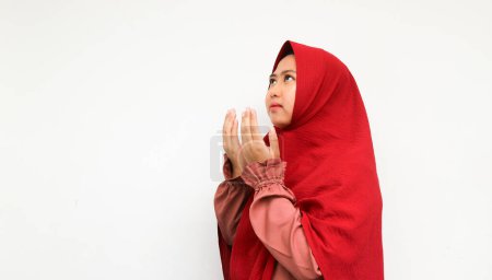 Téléchargez les photos : Femme musulmane asiatique en foulard et hijab prie avec les mains en l'air avec le visage souriant. Une Indonésienne. Religion concept de prière isolé sur fond blanc. - en image libre de droit