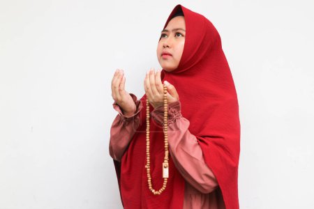 Téléchargez les photos : Femme musulmane asiatique en foulard et hijab prie les mains en l'air en tenant des perles de prière. Une Indonésienne. Religion concept de prière isolé sur fond blanc. - en image libre de droit