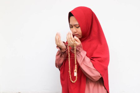 Téléchargez les photos : Femme musulmane asiatique en foulard et hijab prie les mains en l'air en tenant des perles de prière. Une Indonésienne. Religion concept de prière isolé sur fond blanc. - en image libre de droit