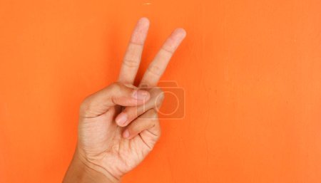 Photo for Hand with peace sign on orange background, human body part concept - Royalty Free Image