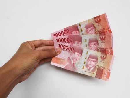 Téléchargez les photos : Main tenant avec un total de trois cent mille rupiah note isolée sur fond blanc. Roupie indonésienne monnaie - en image libre de droit