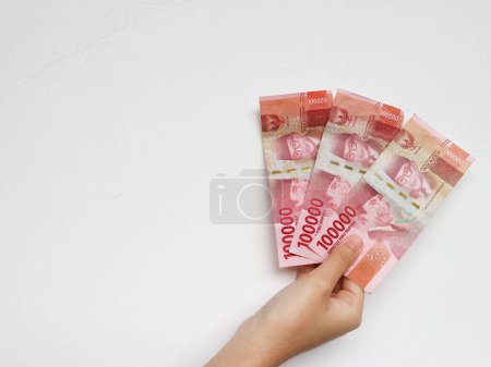 Téléchargez les photos : Main tenant avec un total de trois cent mille rupiah note isolée sur fond blanc. Roupie indonésienne monnaie - en image libre de droit
