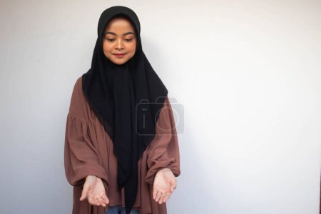 Téléchargez les photos : Jeune Asiatique Islam musulmane en foulard et hijab prie les mains en l'air avec le visage souriant. Une Indonésienne. Religion concept de prière isolé sur fond blanc. - en image libre de droit