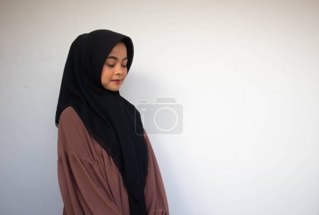 Téléchargez les photos : Jeune Asiatique Islam Femme musulmane en foulard et hijab relaxant avec le visage souriant. Une Indonésienne. Religion concept de prière isolé sur fond blanc. - en image libre de droit