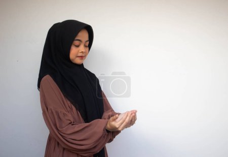 Téléchargez les photos : Jeune Asiatique Islam musulmane en foulard et hijab prie les mains en l'air avec le visage souriant. Une Indonésienne. Religion concept de prière isolé sur fond blanc. - en image libre de droit