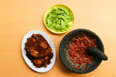 Foto de Ayam Goreng Lengkuas o Galangal Fried Chicken o Ayam Serundeng con salsa de chile o sambal cobek y kacang roay (Phaseolus lunatus) como verdura. concepto de plato indonesio - Imagen libre de derechos