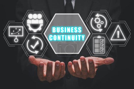 Business continuity concept, Businessman hand holding business continuity icon on virtual screen.