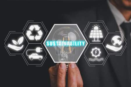 Téléchargez les photos : Concept de durabilité, Businessman main tenant blub lumineux avec icône de durabilité sur écran virtuel. - en image libre de droit